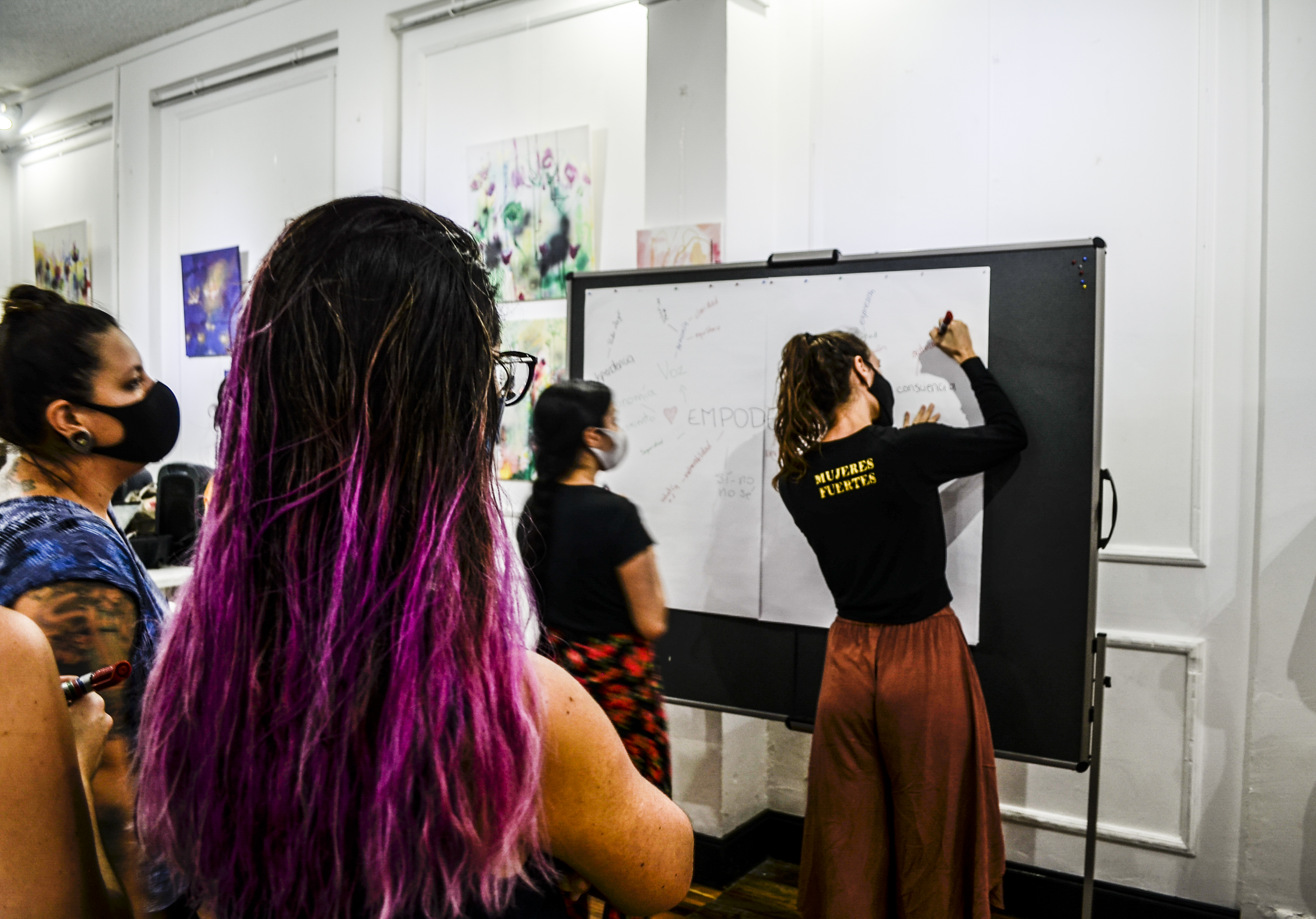 Toby Israel leads a Mujeres Fuertes empowerment workshop, mapping ideas on a whiteboard with participants.